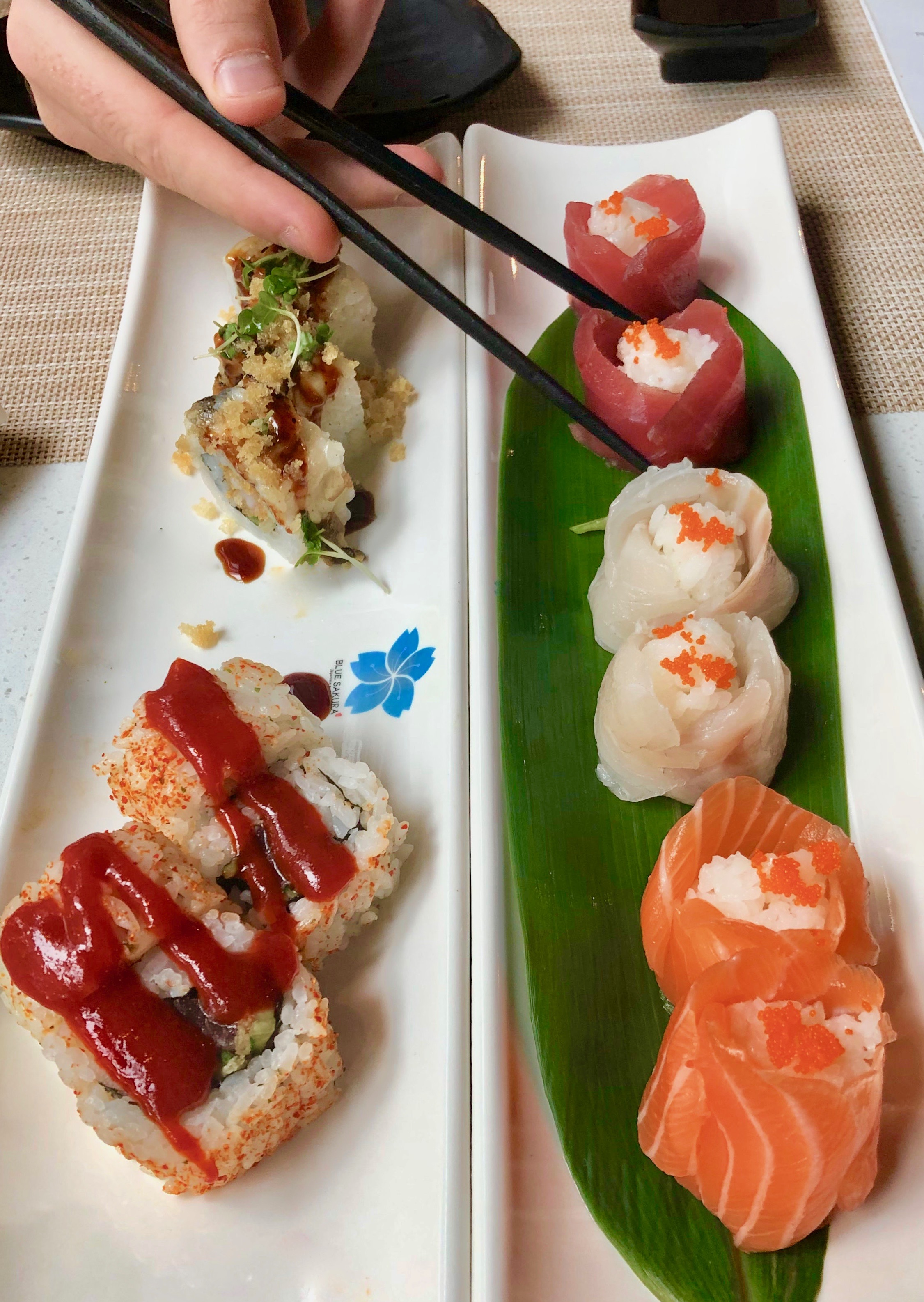 sushi in Leeds: Two long plates of sushi at Blue Sakura, showing different types of sushi and a tuna roll being picked up by chopsticks