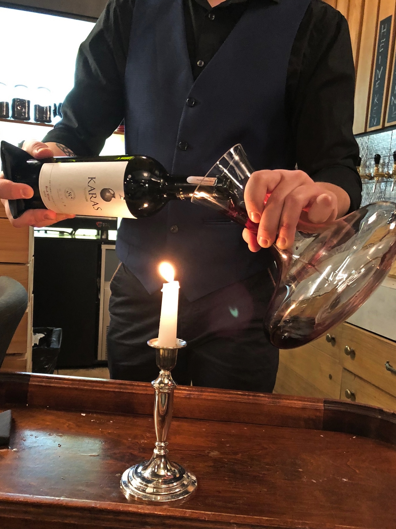 Wine being poured into a decanter over a candle at Somm in Vilnius. Where to eat in Vilnius and Trakai.