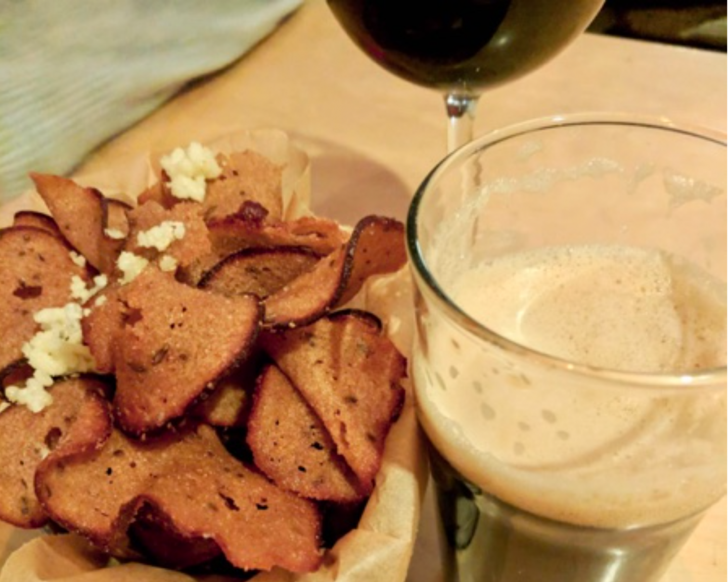 best restaurants in vilnius - a close up of some beer snacks, fried bread, next to a pint of beer and a glass of wine 
