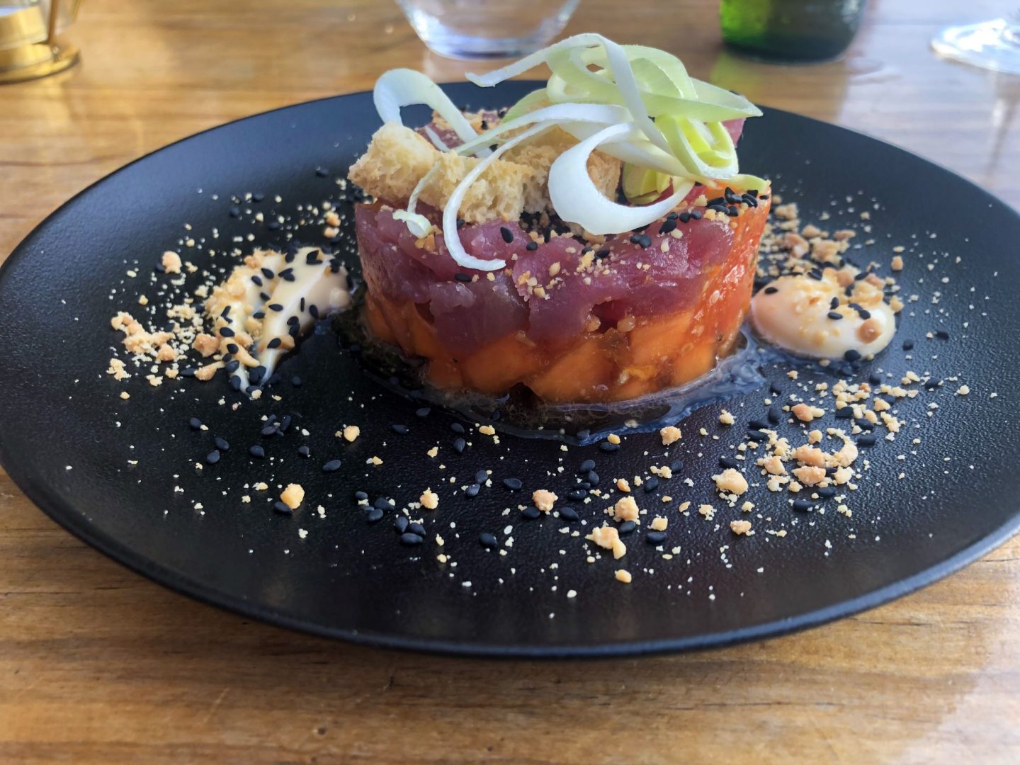 Tuna tartare on a black plate with papaya, spring onion, soy mayonnaise in Gran Canaria