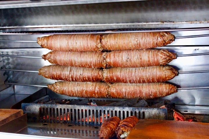 Turkish food in Istanbul: Kokoreç cooking on a spit outside a restaurant in Istanbul, looking like giant sausages over a coal fire.