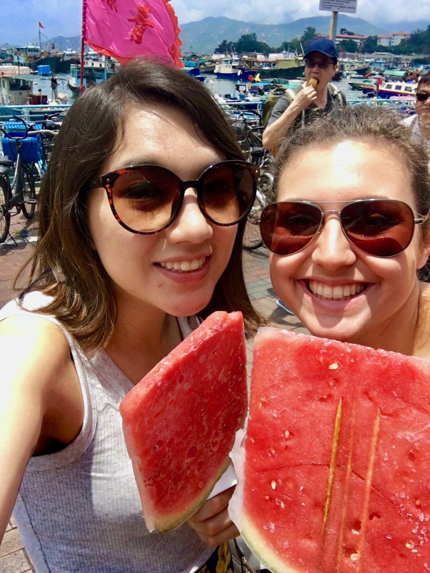 two girls smiling at the camera whilst enjoying frozen watermelon on sticks in hong kong