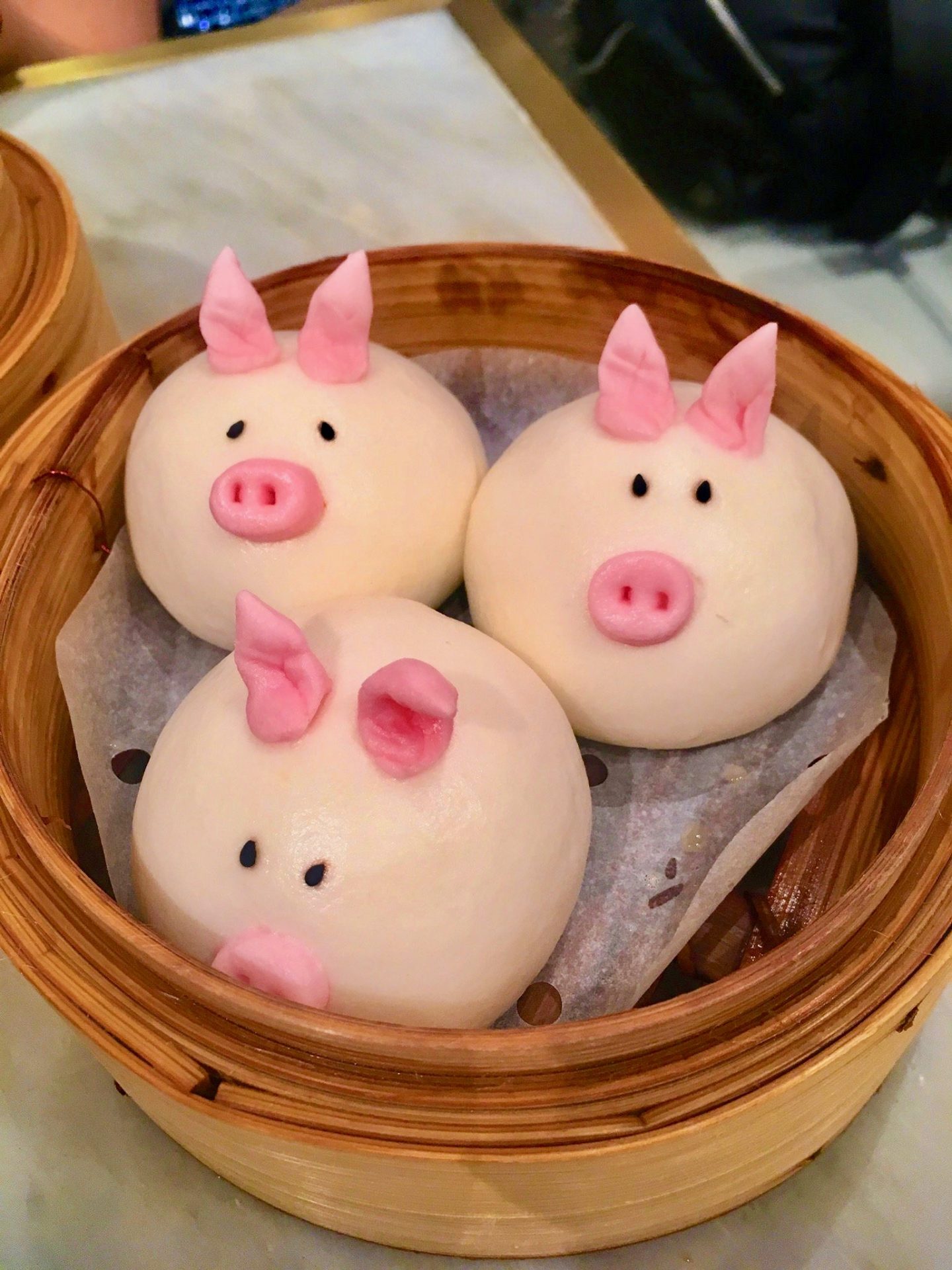 Pork buns decorated to look like pigs with pink snouts and ears! Image shows three pig shaped buns in a steamer and was the best food in hong kong