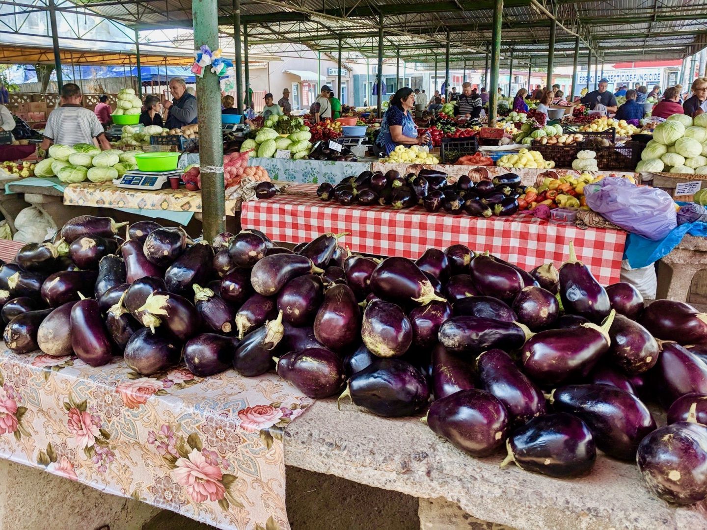 A shot of Turda market, with aubergines in the foreground and varies tables of vegetables in the background