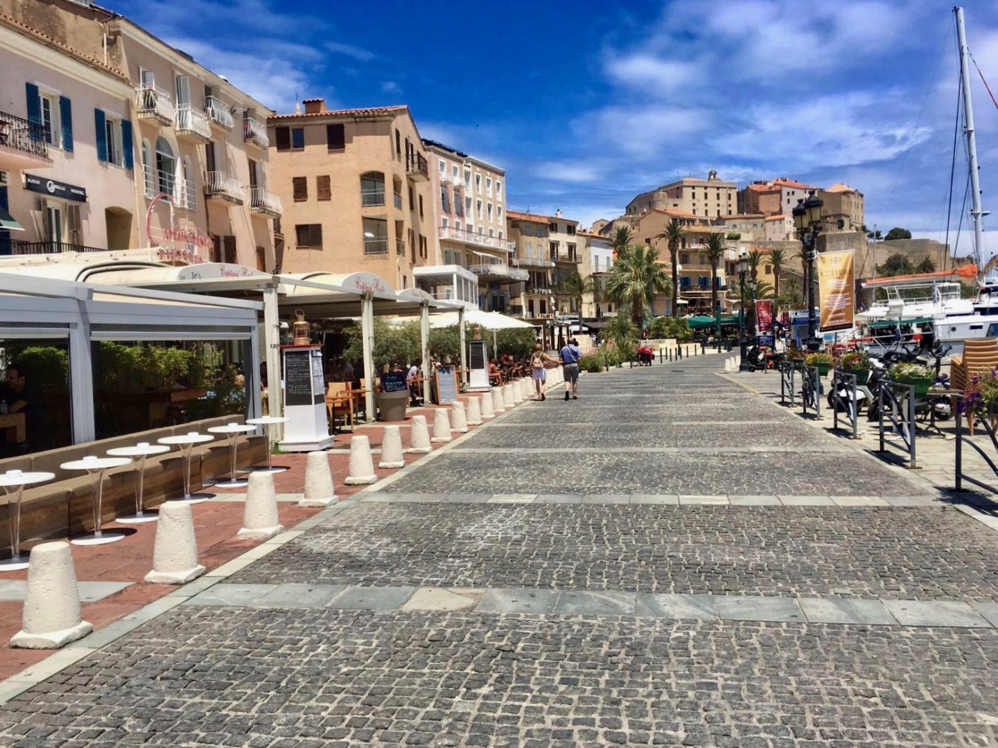 The port of Calvi, showing a cobbled street with boats on one side and restaurants on the other. What to expect on the Gr20
