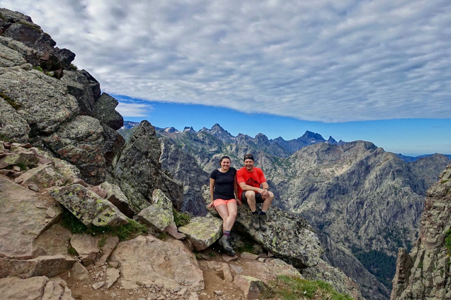 Nell and her dad sat on a rock with stunning mountain views behind them, demonstrating what to expect on the GR20