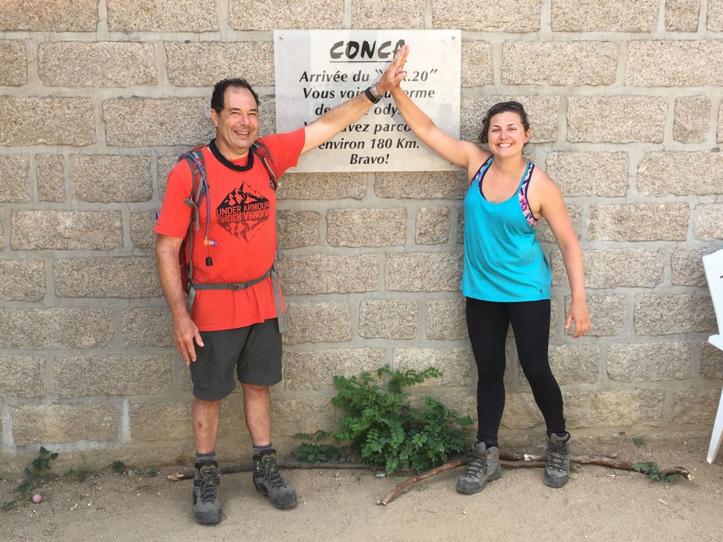 Nell and her dad having a high five next to a sign saying Conca and looking proud to have finished the GR20 - what to expect on the GR20