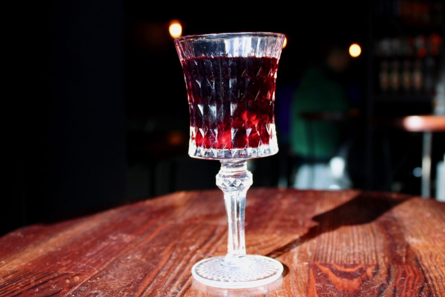 best bars in wroclaw, a glass of cherry liquor on a dark wooden table