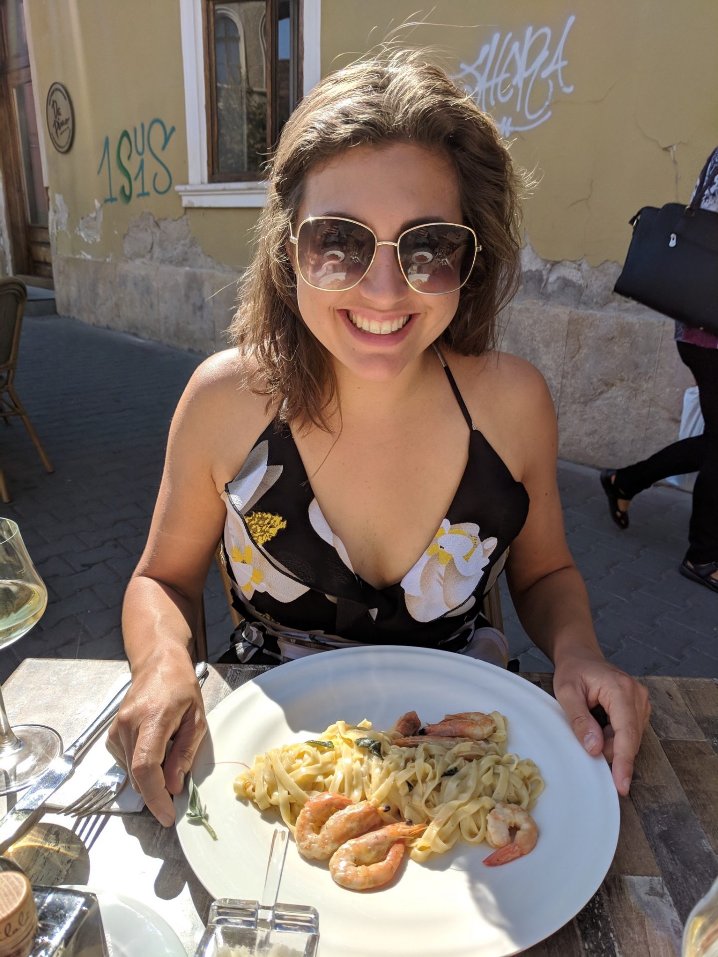 cheap european city break - Nell eating a bowl of pasta in Cluj Napoca. She's wearing sunglasses and looking down at the food whilst smiling